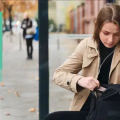 Młoda kobieta szuka czegoś w plecaku. Tekst informuje o konsekwencjach braku dowodu osobistego za granicą i jak to zgłosić.