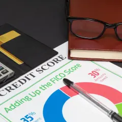 Kalkulator, karty kredytowe, notatnik i okulary na tle dokumentu "Credit Score". Czy po upadłości konsumenckiej można wziąć kredyt?