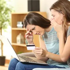 Zmartwione kobiety sprawdzają na laptopie, jak sprawdzić czy ktoś wziął na mnie chwilówkę. Jedna szepcze drugiej.