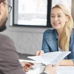 Rozmowa o umowie. Kobieta z uśmiechem podaje dokumenty, zastanawiając się, czy żyrant może się wycofać.
