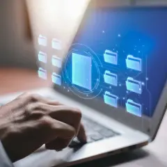 Dłoń na klawiaturze laptopa, wirtualne foldery i dokumenty. Czy raport BIK jest darmowy? Sprawdź online.