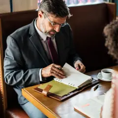 Biznesmen w garniturze przegląda notatki, planując swoje finanse. Może szukać informacji o **novum pozyczki online**.