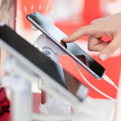 Dłoń dotyka ekranu smartfona, który jest prezentowany jako sprzęt na raty dla zadłużonych.