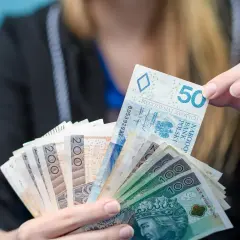 Dłoń trzyma plik polskich banknotów: 50, 100 i 200 zł. Może to być oferta kredytu w Revolut.