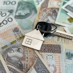 Klucze do domu na stosie polskich banknotów. Rozważasz kredyt inwestycyjny? Sprawdź oprocentowanie!