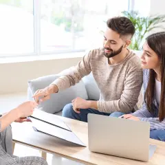 Para omawia z doradcą, jakie są rodzaje kredytów, analizując dokumenty i laptopa.