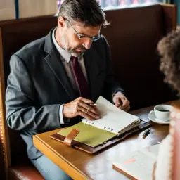 Biznesmen w garniturze przegląda notatki, planując swoje finanse. Może szukać informacji o **novum pozyczki online**.