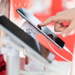 Dłoń dotyka ekranu smartfona, który jest prezentowany jako sprzęt na raty dla zadłużonych.