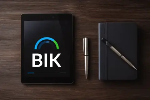 Tablet z logo BIK, symbolem systemu informacji kredytowej i gospodarczej, obok długopis i czarny notes.