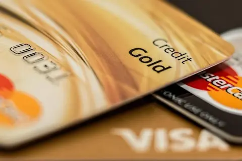 Złota karta kredytowa z napisem "Gold" i numerem 0031. Pod nią widać karty Visa i Mastercard. To przykład, co to kredyt odnawialny.