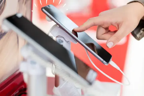 Dłoń dotyka ekranu smartfona, który jest prezentowany jako sprzęt na raty dla zadłużonych.