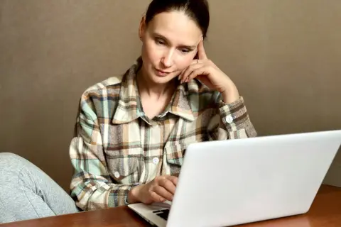 Kobieta zamyślona przy laptopie szuka informacji, jak usunąć negatywny wpis w BIK.