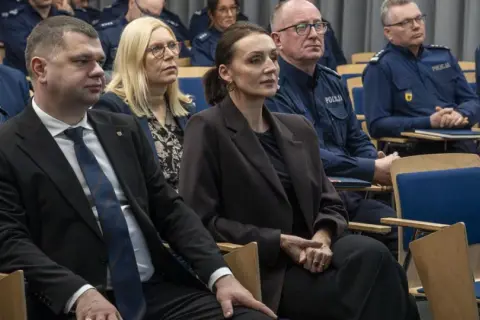 Ludzie w mundurach policyjnych i cywilnych ubraniach siedzą na sali. Dowiedz się, jak sprawdzić numer sprawy na policji.