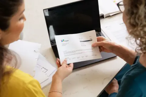 Dwie kobiety analizują dokumenty, szukając rozwiązania, być może ostatniego kredytu dla zadłużonych.