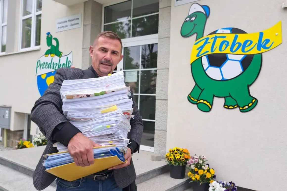 Mężczyzna z dużą stertą dokumentów przed żłobkiem z logo żółwia.