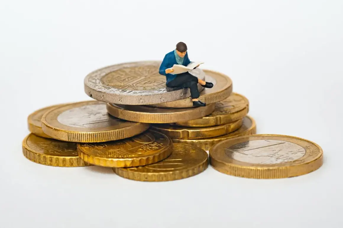Figurka siedzi na stosie monet, czytając. Jak sprawdzić ile ktoś ma długu? Może warto zacząć od analizy finansów, jak ta figurka analizuje swoje monety.