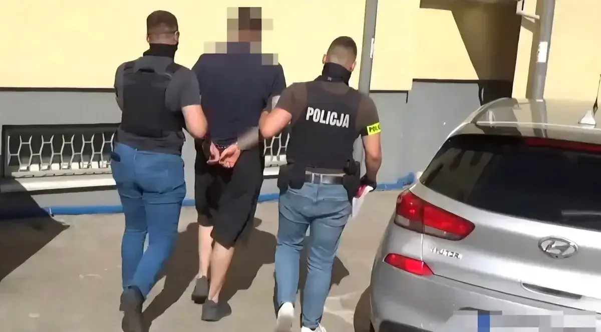 Policja zatrzymała mężczyznę podejrzanego o oszustwa związane z kredytem na telefon. Został wyprowadzony w kajdankach do radiowozu.