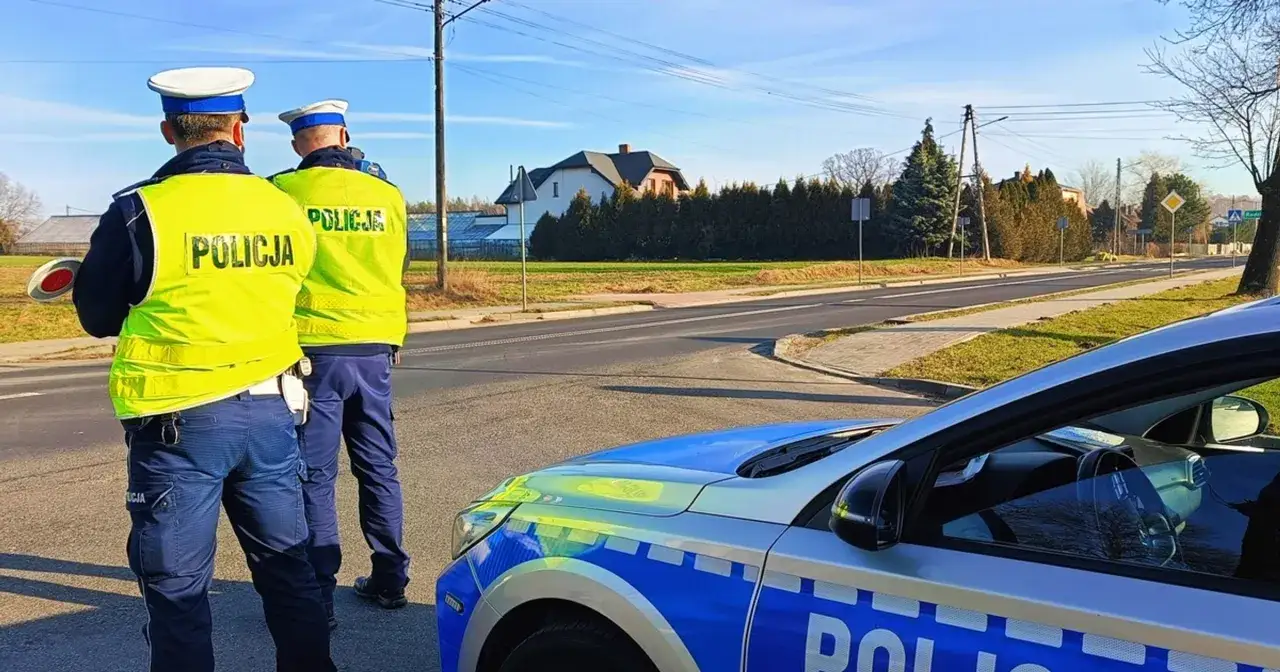 Dwóch policjantów w kamizelkach odblaskowych stoi przy radiowozie. Czy policjant może zabrać dowód osobisty do radiowozu? To pytanie zadaje sobie wielu kierowców.